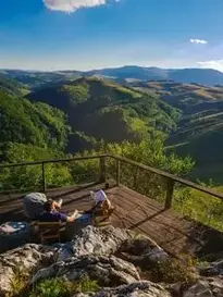 High Angle Photo Of A Man And Woman Sitting on Balcony Viewing Mountains Under Blue and White Sky...