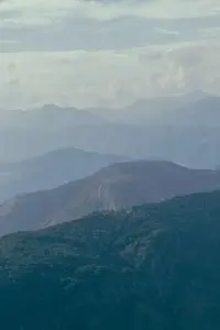 Majestic landscape of mountainous area covered with green trees and plants under cloudy sky phone...