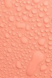 Plain light peach colored with transparent water drops of different sizes and shapes flowing down...