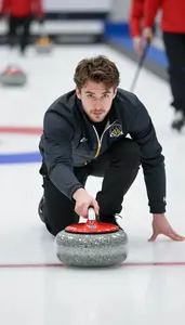 Curling Player In Team Jacket Sliding A Stone Across Smooth