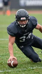 Football Defender In Dark Uniform Sliding To Intercept The