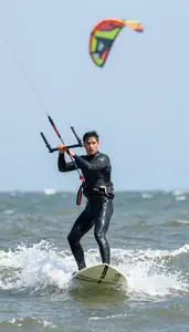 Kite Surfer In Fitted Wetsuit Riding Across Windy Coastal