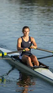 Rowing Athlete In Sleeveless Top Pulling Oars Through Calm