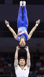 Acrobat In Stretch Costume And Strong Arms Holding A