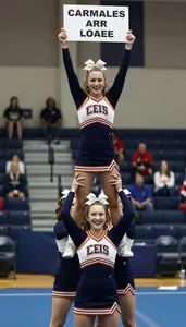 Cheerleader In Uniform And Bow Holding A Flyer High During A