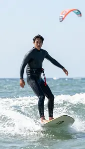 Coastal Kiteboarder In Snug Wetsuit Riding Wind Driven Waves