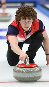 Curler In Team Uniform And Slider Shoe Releasing The Stone