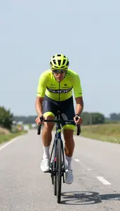 Cyclist In Bright Jersey Racing Along A Flat Countryside