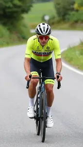 Cyclist In Bright Racing Jersey Pedaling Uphill On Winding