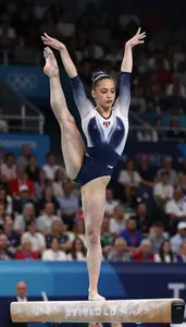 Gymnast In A Leotard Performs A Balance Routine On The Beam