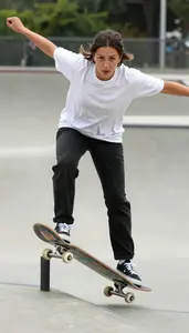 Skateboarder In Loose Sports Tee And Sneakers Grinding Along