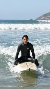Surfer In A Wetsuit Sits On Their Board In The Lineup