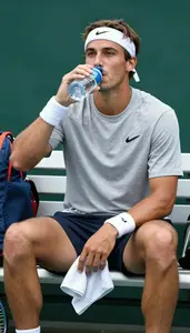 Tennis Player In A Sweatband And Shirt Sits On The Bench