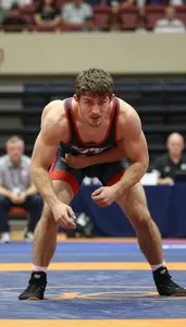 Wrestler In Competition Singlet Grappling Intensely On Mat