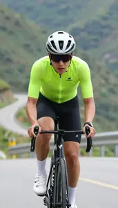 Road Cyclist In Bright Kit And Sunglasses Climbing A Steep