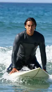 A Surfer In A Snug Wetsuit Sits Patiently On Their Board