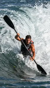 Rafter In Life Jacket Paddling Hard Through A Massive Wave