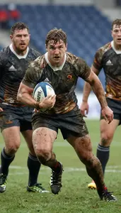 A Rugby Player In A Mud Splattered Jersey And Shorts Charges