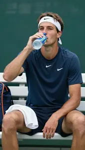 A Tennis Player In A Sweatband And Shirt Sits On The Bench