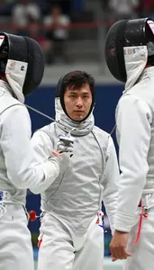 Fencer In A White Jacket Mask Under Arm Talks To A Teammate