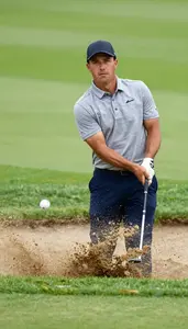 Golfer In A Heather Grey Polo And Navy Trousers Chips From A