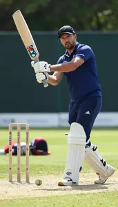 Cricket Coach Hitting A Cricket Ball On A Cricket Match Field At Professional
