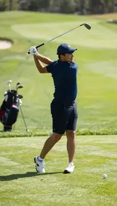 Golf Instructor Swinging A Golf Club On A Golf Course Green In Professional