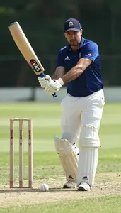 Cricket Coach Hitting A Cricket Ball On A Cricket Pitch In Professional Setting
