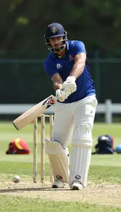 Cricket Coach Hitting A Cricket Ball On A Cricket Pitch At Professional Venue