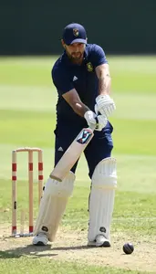Cricket Coach Hitting A Cricket Ball On A Cricket Match Field In Professional
