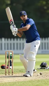 Cricket Coach Hitting A Cricket Ball On A Cricket Match Field In Professional