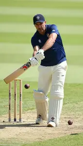 Cricket Coach Hitting A Cricket Ball On A Cricket Match Field At Work Location