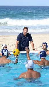 Water Polo Coach Coaching Water Polo Players On A Beach With Ocean Waves At Work
