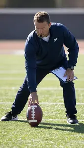 Football Coach Tackling A Football On On An American Football Field In