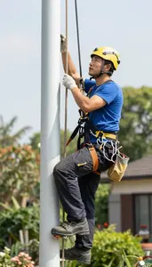 Landscaper Climbing A Wind Turbine In A Residential Garden At Workplace