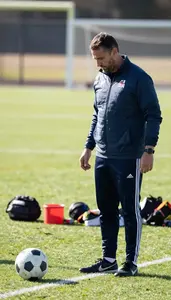 Soccer Coach Kicking A Soccer Ball On A Soccer Match Field At Work Location
