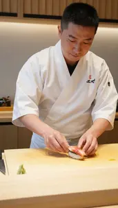 Sushi Chef Serving Sushi With Precision At A Sushi Bar Counter At Professional