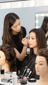 Wig Stylist Applying Professional Makeup To In A Wig Styling Workshop In