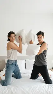 Friends Having A Pillow Fight In A Bright White Hotel Room