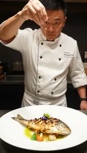 Chef Sprinkling Salt From High Above A Perfectly Seared Fish Dish
