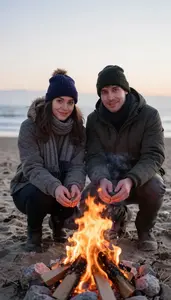 Couple Warming Their Hands By A Bonfire On A Cold Beach