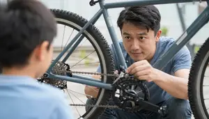 Dad Fixing A Bicycle Chain While His Son Watches And Learns