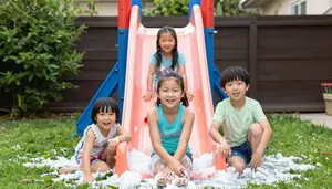 Family Creating A Messy Slip And Slide With Soap In The Backyard