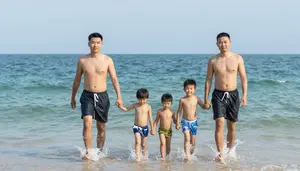 Family Walking Into The Ocean Together Holding Hands For A Swim