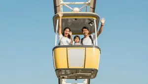 Family Waving From A Ferris Wheel Bucket High In The Air