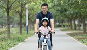 Father Standing Protectively Behind His Daughter On Her First Bicycle