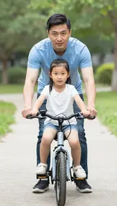 Father Teaching His Young Daughter How To Ride A Bicycle